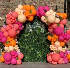 an orange and pink balloon arch with the words let's party on it