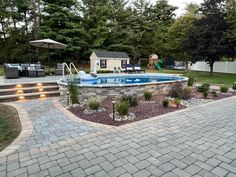 an outdoor swimming pool surrounded by landscaping and steps leading up to the back yard area