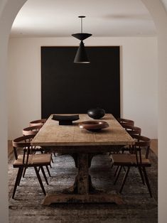 a dining room table and chairs in front of a black wall with an arched doorway