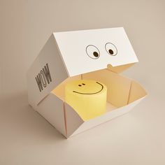 an open box with a smiley face on it and a yellow candle in the middle