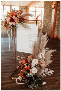 a sign that is sitting on top of a wooden floor next to flowers and feathers