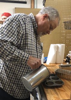 a man pouring something into a cup on top of a stove