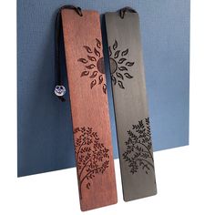 two wooden bookmarks with designs on them hanging from a blue and white wall next to each other