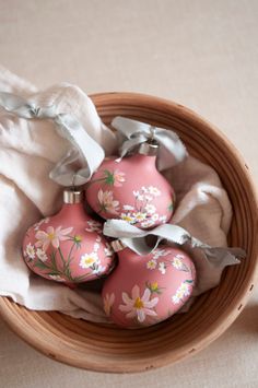 three pink ornaments are in a basket on the floor