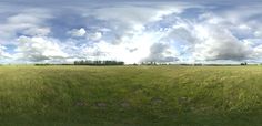 an empty field with clouds in the sky