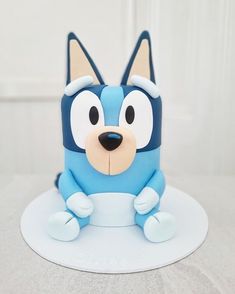 a cake that looks like a cartoon character sitting on top of a white plate with blue frosting