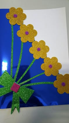 a blue vase filled with yellow flowers on top of a white table next to a green bow