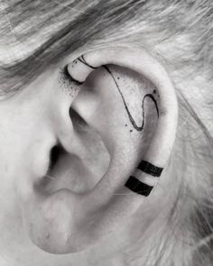 a woman's ear with the word love on it and an arrow tattoo behind her ear