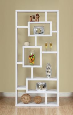 a white shelving unit with several shelves and vases on the top, in front of a beige wall