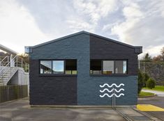 a black house with white waves painted on it's side and stairs leading up to the second floor