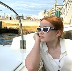 a woman wearing sunglasses sitting on the back of a boat