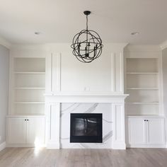 an empty living room with a fireplace and built in bookshelves