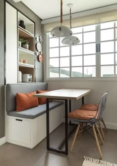 a room with a table, bench and window in the corner next to a chair