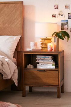 a bed with a wooden headboard and night stand next to a nightstand filled with books