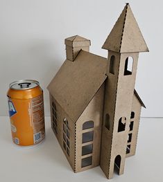 a cardboard house next to a can of soda