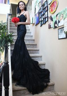 a woman in a black dress is standing on the stairs with flowers and red carnations