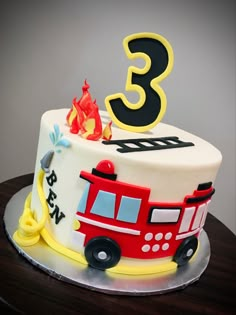 a birthday cake with the number three on top and firetruck decorationating it