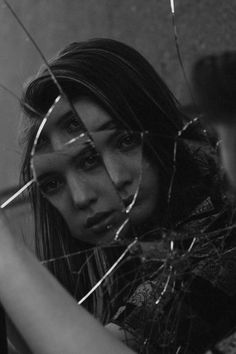 a woman looking through some barbed wire with her hand on the back of her head