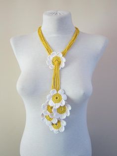 a white mannequin wearing a yellow and white necklace