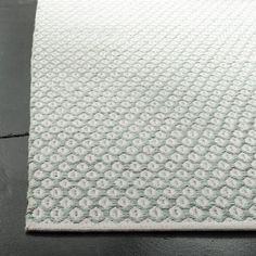 a white rug on top of a black tile floor with an area rug in the middle