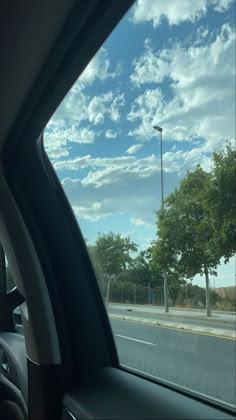 the view from inside a car looking out at an empty street with trees on both sides