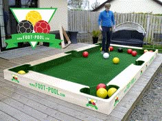 a man standing on top of a green pool filled with balls