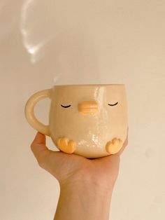 a hand holding a coffee mug with eyes closed