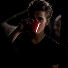 a man drinking from a red cup in the dark