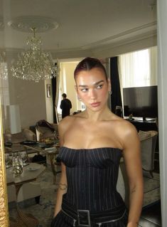 a woman standing in front of a mirror wearing a strapless top and black pants