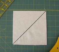 a pair of scissors sitting on top of a cutting board next to a piece of fabric