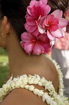 a woman with flowers in her hair is wearing a white and pink flowered dress