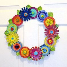 a colorful paper flower wreath hanging on the front door to decorate it's doors