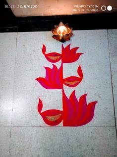 a candle is lit on the floor next to a flower design that looks like leaves