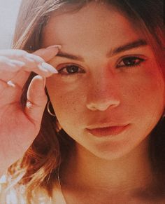 a close up of a woman holding a cell phone to her ear and looking at the camera