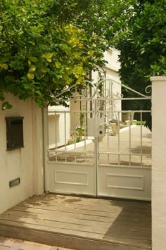 an open white door leading to a house with trees growing on it's sides