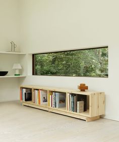 there is a book shelf with books on it in front of a window and shelves below