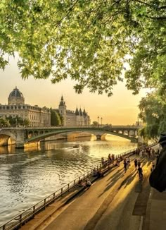 people are walking along the river in paris, france at sunset or dawn with some bridges and buildings on either side