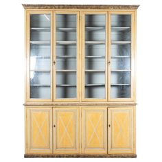 an antique china cabinet with glass doors and wood trimmings on the front, against a white background