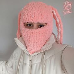 a woman wearing a pink bunny ears hat and scarf over her face with the hood pulled back