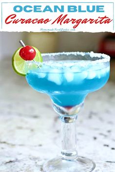 a blue margarita in a martini glass with a cherry on the rim