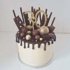 a white cake with chocolate and gold decorations on it's top that says 30