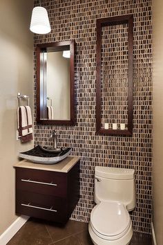 a bathroom with a toilet, sink and mirror in it's corner area next to a tiled wall