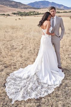 a bride and groom standing in an open field