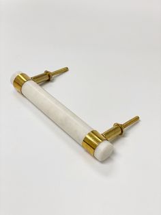 a white and gold object on a white surface with two brass posts sticking out of it