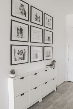 a white room with pictures on the wall and some drawers in front of it,