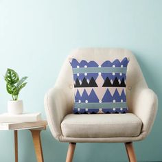 a blue and white pillow sitting on top of a chair next to a potted plant