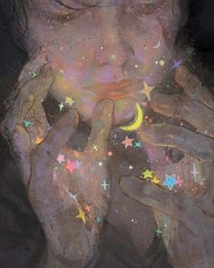 a woman is holding her hands up to her face with stars and moon painted on it