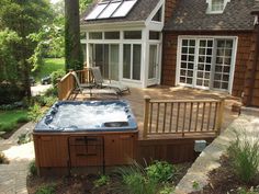 a hot tub sitting on top of a wooden deck next to a building with sliding glass doors