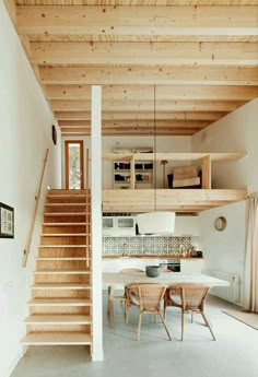 a kitchen and dining area with stairs leading up to the second floor in this modern home