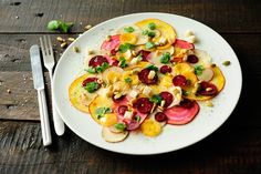 a white plate topped with sliced up radishes and other veggies next to a fork